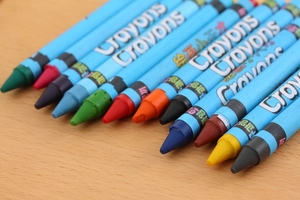 Close-up of colorful twistable crayons with blue barrels on a light wood surface