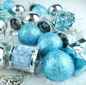 Close-up of 32-piece set blue and silver Christmas ornaments on white plush background