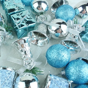 Close-up of blue glitter baubles and silver bells with bows on a white plush rug
