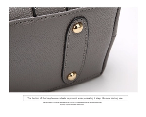 Detailed macro view of the grey leather bag base featuring protective gold-tone metal studs