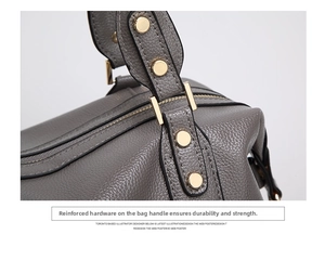 Detail of grey lychee leather texture and golden metal hardware on a boston bag