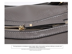 Detail shot of golden metal zipper and grey lychee grain leather texture on a Boston bag