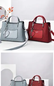 Détail du petit sac à main carré avec plis verticaux et breloque métallique en forme de cœur