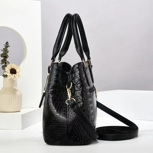 Detail view of black crocodile pattern handbag with gold hardware and side zipper pocket
