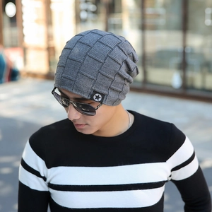 Detail of grey knitted beanie with star patch against a blurred outdoor city background