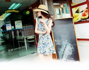 Close-up of a floral sleeveless dress with lace trim and a beige straw sun hat for summer