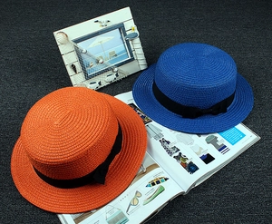 Close-up of bright orange and royal blue boater straw hats with black ribbon bows