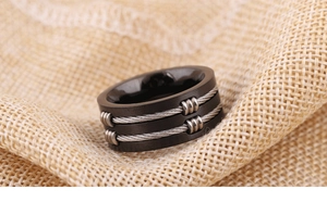 Close-up of 8mm black titanium steel ring with silver cable inlay on burlap background
