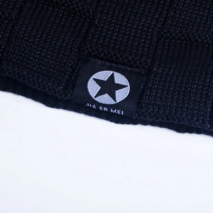 Close-up of black knitted winter beanie showing fabric texture and stitched brand label