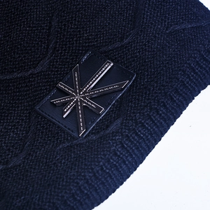 Macro shot of black knit beanie texture and star metal badge with diamond base