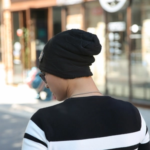 Detail of a black knit beanie with a stylish metal plaque and cozy winter texture