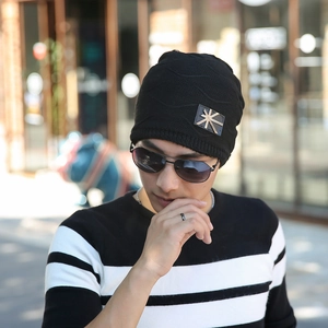 Close-up of black winter knit beanie featuring a premium gold cross metal patch detail