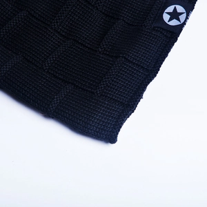 Detail of black knit beanie featuring checkerboard weave texture and star label patch