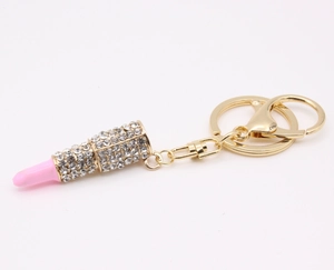Detail view of gold-tone metal lipstick keychain with sparkling rhinestones and lobster clasp