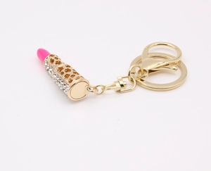 Close-up of golden keychain with sparkling rhinestone-studded lipstick and pink tip