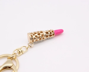 Close-up of golden lipstick keychain featuring pink details and sparkling rhinestones