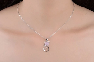 Close-up of a silver cat pendant necklace with a round pink quartz stone on female model