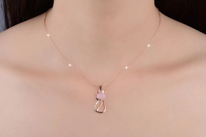 Detailed view of rose gold cat pendant necklace with pink crystal on model