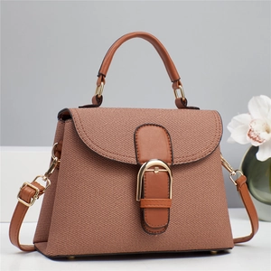 Detail of brown twill fabric handbag with leather handles and gold metal clasp closure