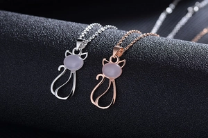 Close-up of cat-shaped pendants in silver and rose gold with inlaid rose quartz stones