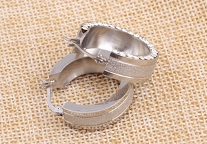 Detail of 8mm silver stainless steel huggie earring with frosted finish and cubic zirconia