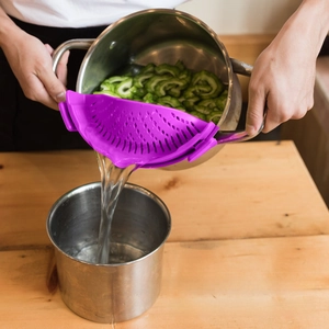 Close-up of purple clip-on silicone strainer draining water from a pot of vegetables