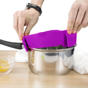 Macro view of purple silicone clip-on pot strainer filtering water from a steel saucepan