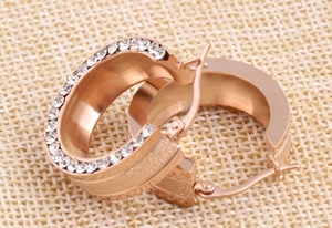 Macro detail of rose gold 8mm hoop earrings with frosted finish and inlaid crystals