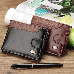 Détail de portefeuilles en cuir noir et marron avec texture croco et logo métal