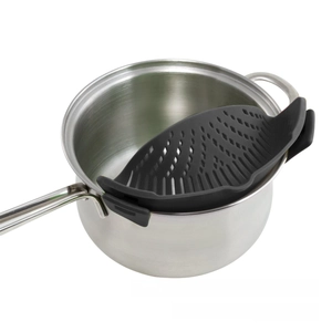 Macro shot of dark grey silicone clip-on pot strainer filtering noodles on a metal pan