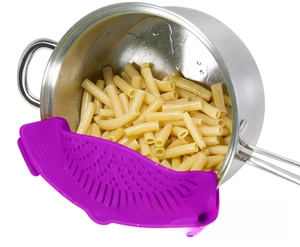Purple silicone clip-on pot strainer filtering water from pasta in a metal cooking pot