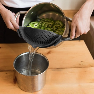 Detailed view of gray silicone clip-on pot strainer filtering water from vegetables