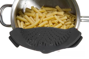 Close-up of gray silicone clip-on pot strainer filtering pasta from a stainless steel pot