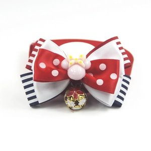 Close-up of pet bowtie accessory with polka dots, stripes and a small metal bell
