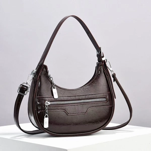 Detail of dark brown crescent bag showing the oil leather texture and front zipper pocket