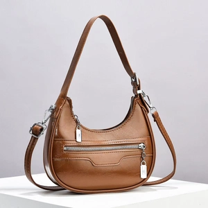 Detail view of brown crescent shoulder bag with glossy finish and silver metal zipper accents