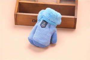 Detail of blue knitted toddler winter glove with plush cuff and small brand label