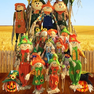 Standing Halloween scarecrow dolls and pumpkin ornaments in a sunny autumn wheat field