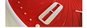 Detail of red wall clock dial with 3D white dot markers and radiating relief texture