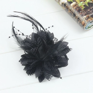 Elegant black feather hair accessory with lace flower petals and beads on white wood