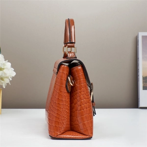 Detail view of brown crocodile texture leather bag with shiny gold metal hardware