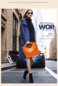Orange lychee texture leather handbag styled with a blue coat in a modern urban street setting