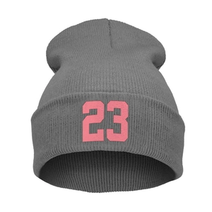 Dettaglio di un berretto in maglia grigio scuro con ricamo rosa numero 23 a contrasto