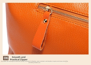 Detailed close-up of smooth gold metal zipper and orange lychee grain leather handbag