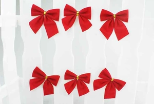 Set of six red velvet Christmas bows with gold ties on a white picket fence background