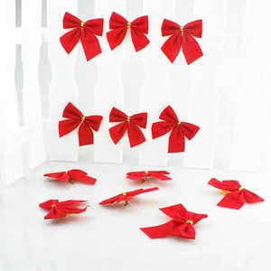 Set of 12 red velvet Christmas bows with gold ties on a white decorative fence