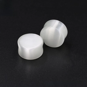 Macro shot of polished white cat eye stone ear plugs with smooth reflective finish