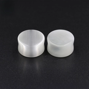 Macro shot of white cat eye stone ear plugs showing silky fiber texture on dark background