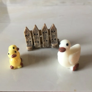 Miniatura de resina con patos amarillos y blancos junto a una valla de jardín