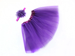 Flat lay of purple chiffon tutu skirt and matching floral headband for baby photography